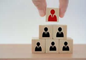 hand putting wooden block on top stack of cube, pyramid shape, for human resource management and recruitment business concept